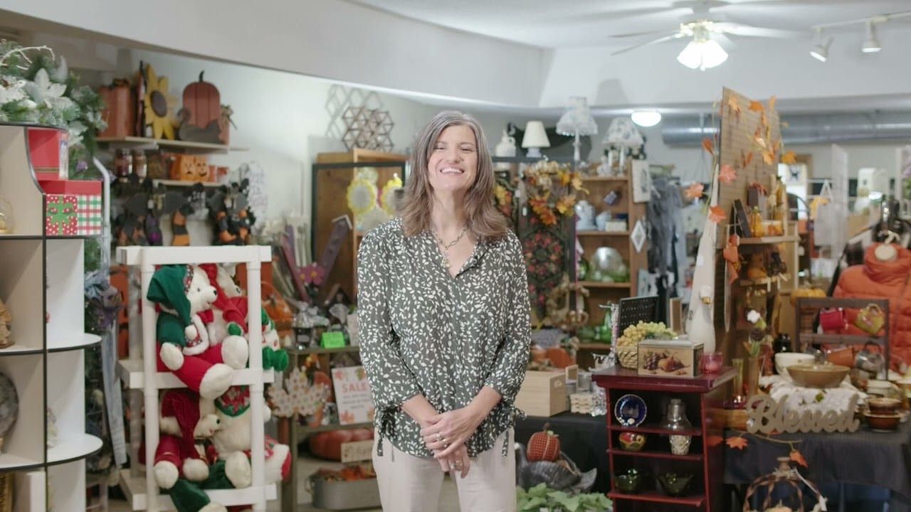 Woman standing in a warmly lit store filled with antiques and various decorative items
